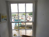 24KirkGallery  The Harbour through a gallery window with boats in the forground Kirkcudbright